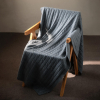 Manta de cashmere gris medio con punto de ochos sobre una silla de madera
