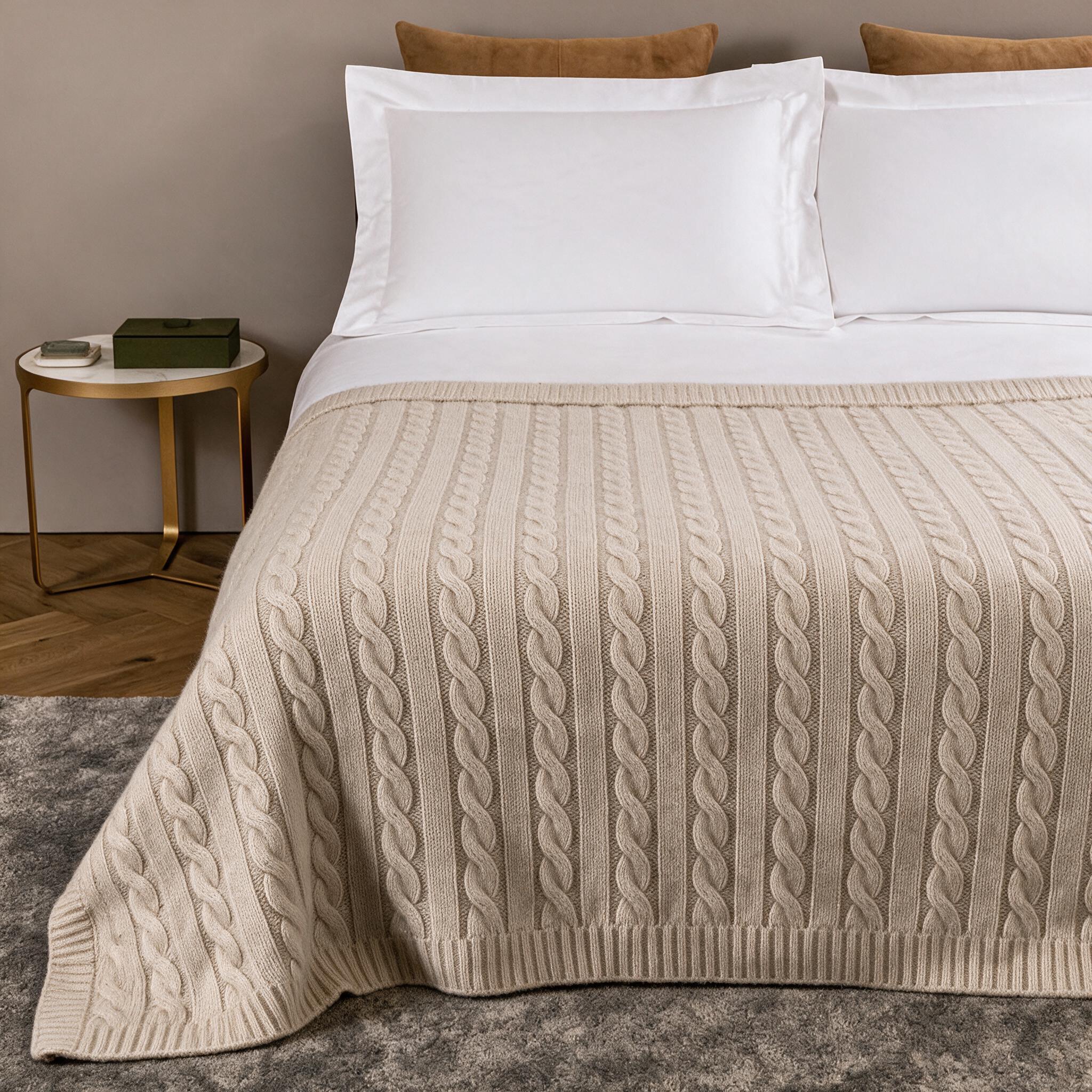 Manta de cashmere de ochos en avena a los pies de una cama vestida de blanco