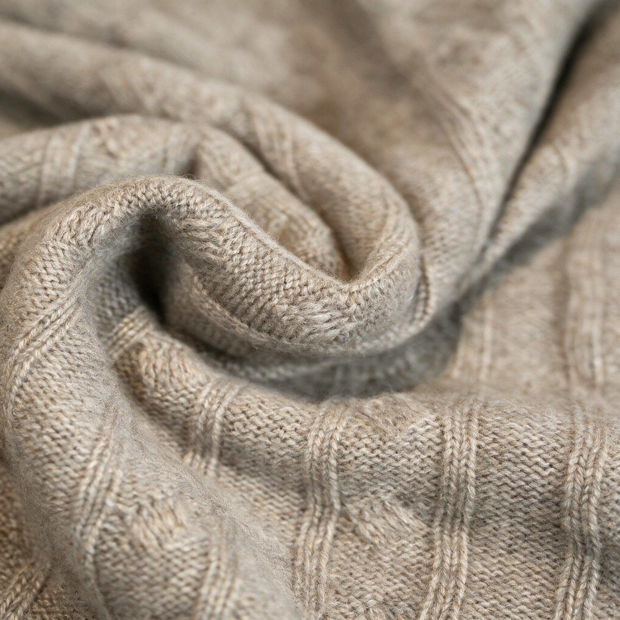 Soft folds of oatmeal cashmere showing the fine knit texture