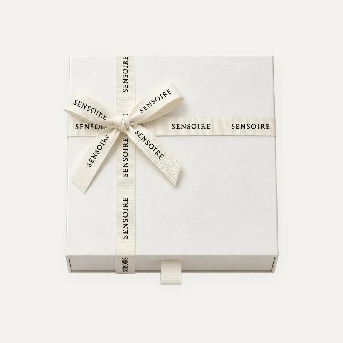 Ivoorkleurige Sensoire cadeaudoos met een crèmekleurig grosgrain lint waarop de naam Sensoire staat