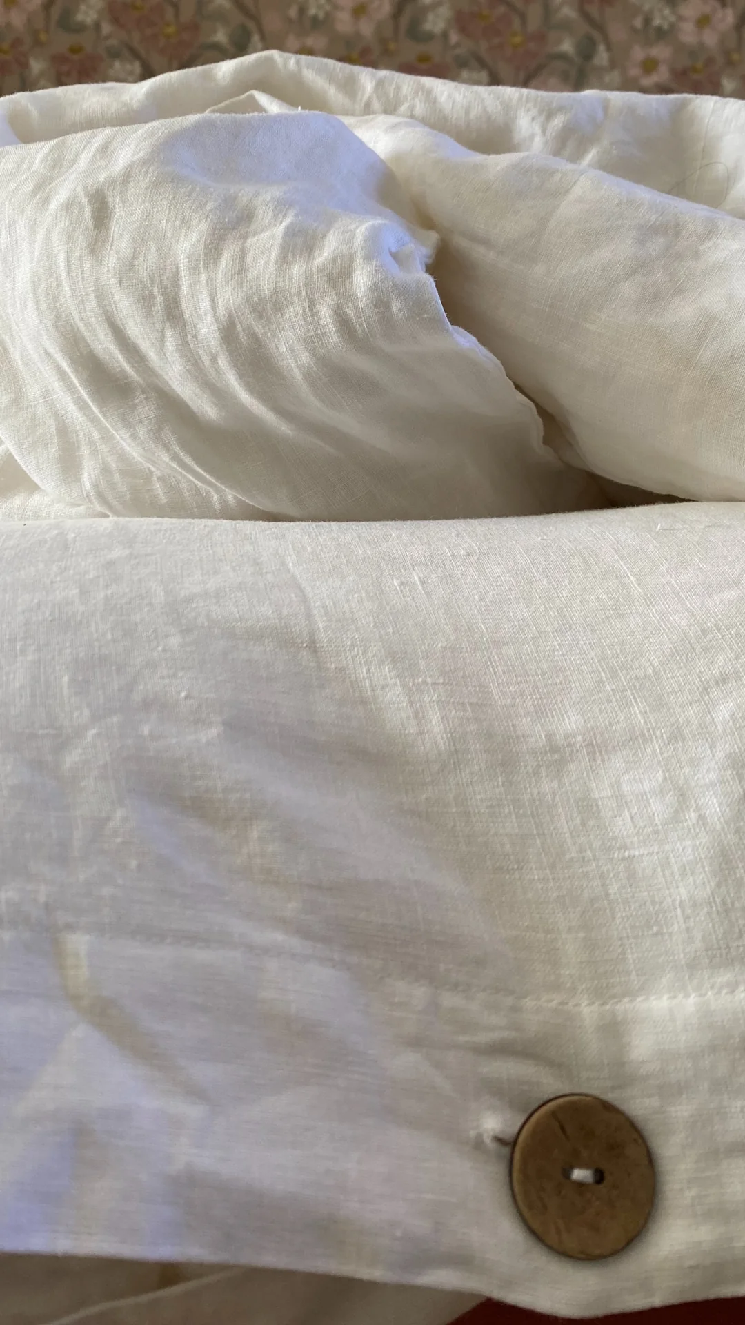 Gros plan sur une housse de couette Sensoire en lin lavé blanc à bouton en noix de coco, chez Marie