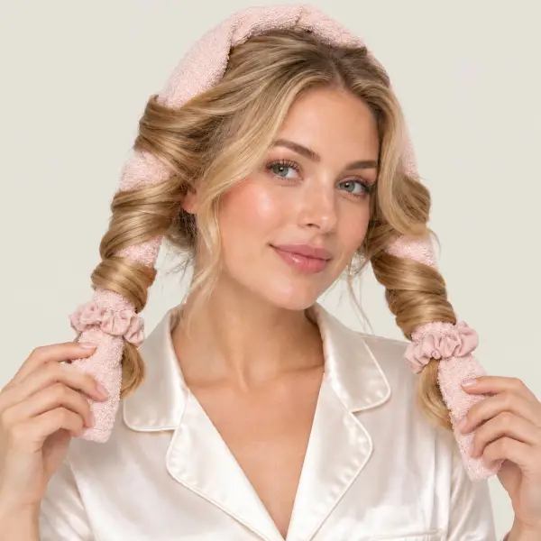 Vrouw met het haar in een zachte roze handdoek gewikkeld voor krullen zonder hitte