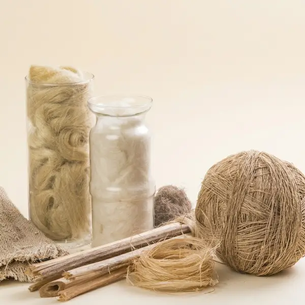 Ruwe vlasvezel in glazen potten met vlasstengels, een bol linnengaren en een linnen stofstaal