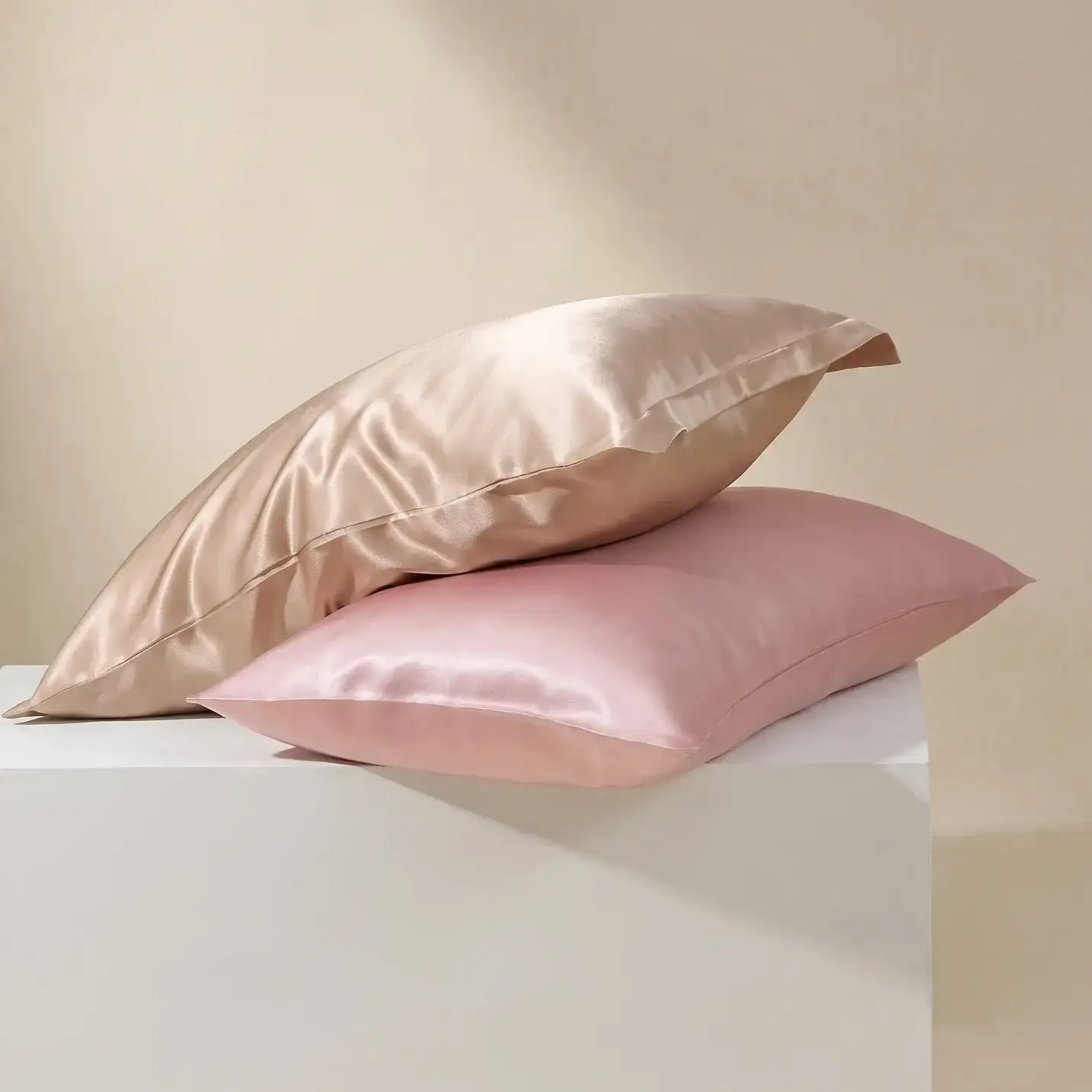Federa in seta champagne con bordo Oxford appoggiata su una federa in seta rosa cipria