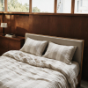 Taies en lin à rayures naturelles et housse de couette légèrement froissée sur un lit