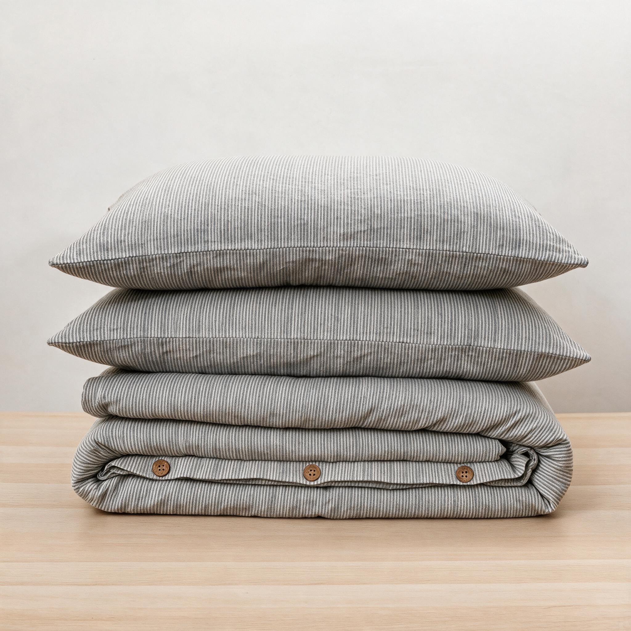 Housse de couette en lin à rayures anthracite, pliée, et deux taies, boutons en noix de coco